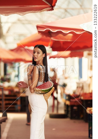 Just bought the watermelon. Young woman is on the vegetable market or bazaar Just bought the watermelon. Young woman is on the vegetable market or bazaar 133222619
