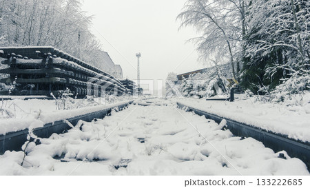 Quiet industrial zone blanketed in snow with distant factory outlines Quiet industrial zone blanketed in snow with distant factory outlines 133222685