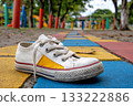 White and yellow child's shoe abandoned on colorful playground path 133222886