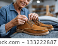 Senior woman tying shoelaces on new suede boots in store 133222887