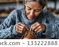 Shoemaker tying shoelaces on handmade leather boots in workshop 133222888