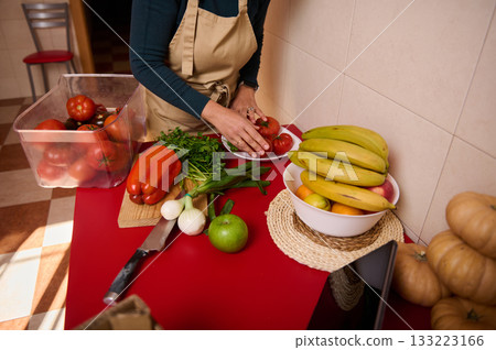 Home Cooking: Person Preparing Fresh Vegetables And Fruit On Red Counter Home Cooking: Person Preparing Fresh Vegetables And Fruit On Red Counter 133223166