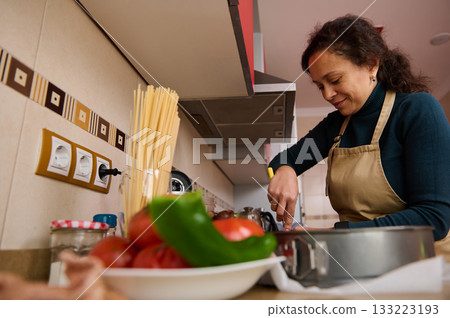 Woman In Apron Cooking In Kitchen, Preparing Pasta With Pan 133223193