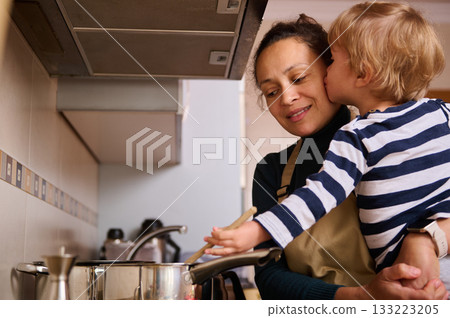 Mother And Child In The Kitchen Sharing A Kiss While Cooking Together Joyfully At Home 133223205