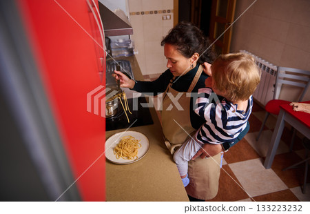Mom Cooking Pasta With Child In Kitchen, Family Meal, Home Cooking Moment Mom Cooking Pasta With Child In Kitchen, Family Meal, Home Cooking Moment 133223232