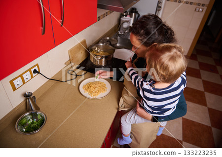 Mother And Child Cooking Pasta In A Red Kitchen 133223235