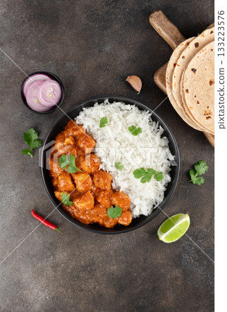 Indian butter chicken with basmati rice, roti, onion, lime and herbs on gray background. Top view Indian butter chicken with basmati rice, roti, onion, lime and herbs on gray background. Top view 133223576