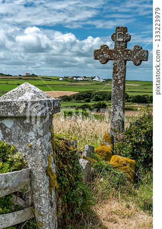 Stone cross is in a field with a fence and a stone wall Stone cross is in a field with a fence and a stone wall 133223979