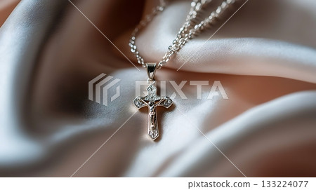 Silver cross necklace is on a white cloth Silver cross necklace is on a white cloth 133224077