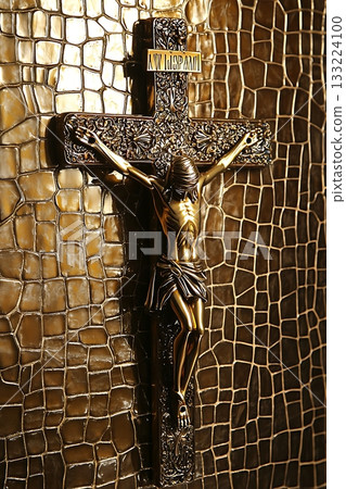 Gold cross with a man on it is hanging on a wall 133224100
