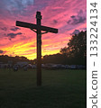 Cross with Jesus Christ on top of it is standing in a field 133224134