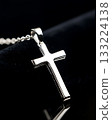 Silver cross pendant is on a black background 133224138