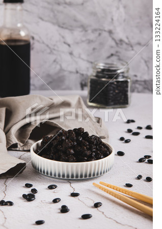 Fermented black douchi beans in a bowl on the table vertical view 133224164