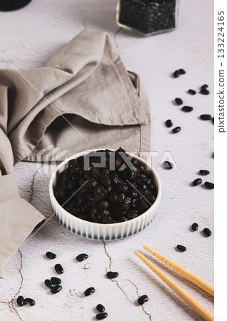 Asian fermented black beans on a plate on the table vertical view Asian fermented black beans on a plate on the table vertical view 133224165