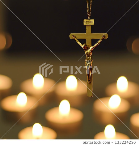 Gold cross with the name Jesus hanging from it is suspended above a lit candle 133224250