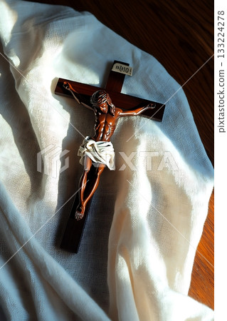 Wooden cross with a man on it is on a white cloth Wooden cross with a man on it is on a white cloth 133224278