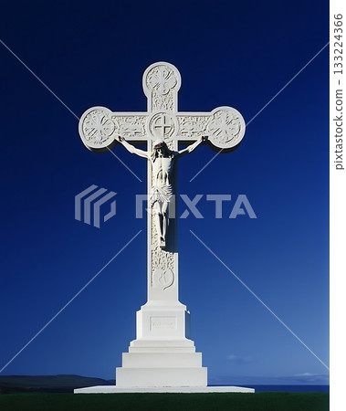 White cross with a statue of Jesus Christ on top of it 133224366