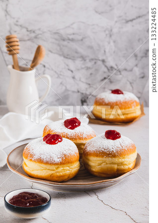 Sweet donuts in powdered sugar with jam on a plate on the table vertical view 133224485