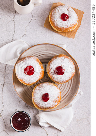 Delicious jam filled donuts with powdered sugar on a plate on the table top and vertical view Delicious jam filled donuts with powdered sugar on a plate on the table top and vertical view 133224489