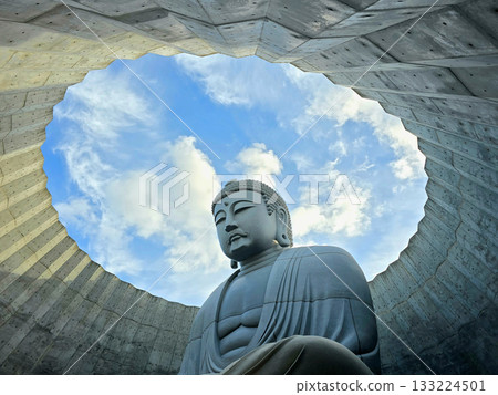 The serene Buddha statue is set against a backdrop of a bright blue sky, creating a sense of peace and tranquility The serene Buddha statue is set against a backdrop of a bright blue sky, creating a sense of peace and tranquility 133224501