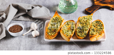 Baked baguette with butter, garlic and dill on a plate on the table web banner 133224586
