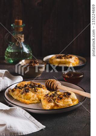 Baked pumpkin with brie cheese, nuts, rosemary and honey on a plate on the table vertical view Baked pumpkin with brie cheese, nuts, rosemary and honey on a plate on the table vertical view 133224669