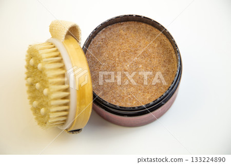 Body scrub in a round container with a wooden brush, highlighting its rich texture and inviting aroma, ideal for enhancing skincare and self-care experiences Body scrub in a round container with a wooden brush, highlighting its rich texture and inviting aroma, ideal for enhancing skincare and self-care experiences 133224890