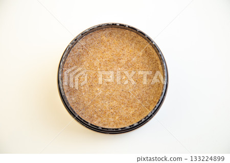 Black round container features a brown textured substance, highlighting smoothness and subtle variations, perfect for culinary or cosmetic use, with ample copy space for branding 133224899