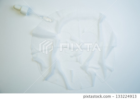 Sheet mask and dropper placed on a pristine white background, highlighting skincare essentials and promoting beauty rituals for rejuvenating and nourishing skin 133224913
