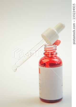 Glass dropper bottle filled with vibrant red liquid, featuring a pipette, perfect for skincare and cosmetic use, highlighting product design and elegance 133224915