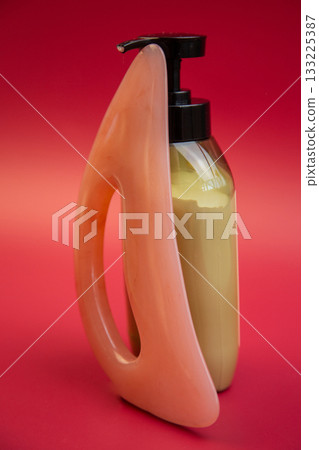 Modern bottle design with a pump dispenser and soft pink handle, filled with yellow liquid, set against a bold red background, ideal for promotional use 133225387