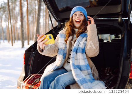 Selfie time. Young Woman sitting in trunk of car and taking selfie in winter forest. Rest, blogging. 133225494