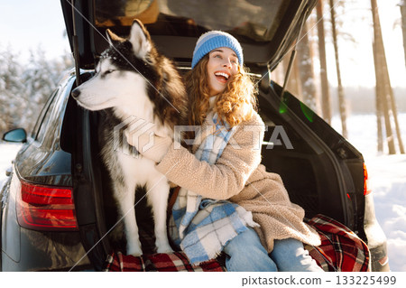 Woman with husky dog have picnic in car trunk near pine forest, traveling by car. Travel concept. Woman with husky dog have picnic in car trunk near pine forest, traveling by car. Travel concept. 133225499