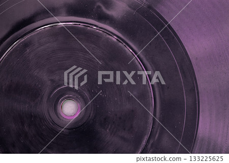 Close-up of old vinyl record or plastic disc with scratches, spots and cracks, in purple hue. Concept of retro music, abstract vintage sound background or grainy analog texture Close-up of old vinyl record or plastic disc with scratches, spots and cracks, in purple hue. Concept of retro music, abstract vintage sound background or grainy analog texture 133225625