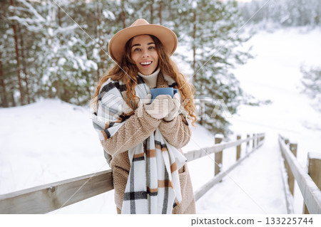 Young woman drinks hot tea while holding a thermos in nature. . Vacation concept 133225744
