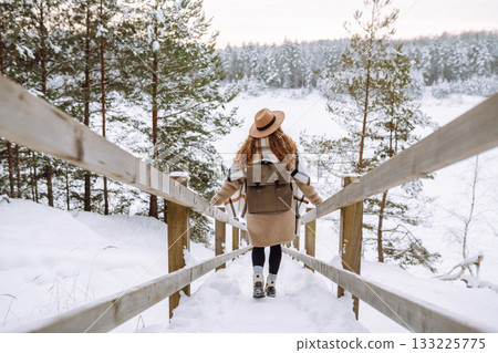 Woman traveler in a hat with a backpack on a wooden ladder. Active lifestyle. Travel concept. 133225775