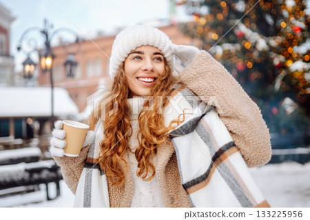 Woman is having fun at a street holiday fair, drinking a hot drink. Winter holidays. Lifestyle. Woman is having fun at a street holiday fair, drinking a hot drink. Winter holidays. Lifestyle. 133225956