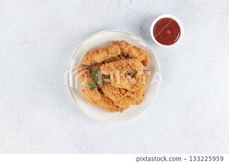 Crispy chicken strips with ketchup on a white background. Top view. Fast food. Crispy chicken strips with ketchup on a white background. Top view. Fast food. 133225959