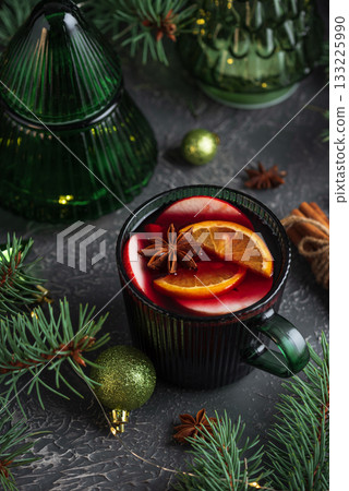 Holiday Mulled Wine with Orange and Apple in Green Mug Surrounded by Christmas Decor 133225990