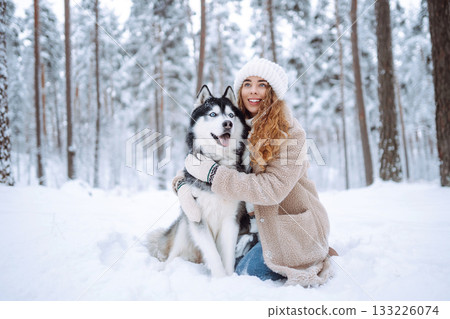 Cute woman spends time with her husky dog in the winter snowy forest. Lifestyle. Cute woman spends time with her husky dog in the winter snowy forest. Lifestyle. 133226074