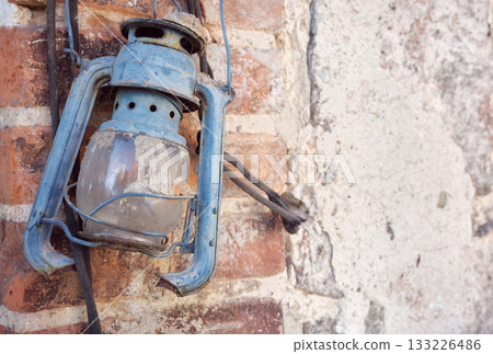 Rusty old damaged kerosene lamp on a wall, selective focus. Rusty old damaged kerosene lamp on a wall, selective focus. 133226486