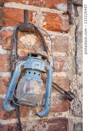 Rusty old damaged kerosene lamp on a wall, selective focus. Rusty old damaged kerosene lamp on a wall, selective focus. 133226487