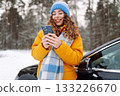 Young woman with phone near her car in a winter forest. Sending messages, communicating with friends 133226670