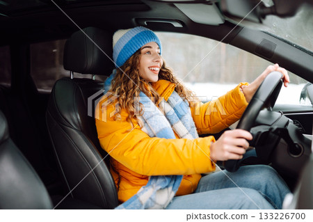 Happy woman in winter outfit driving car. The concept of transport, lifestyle. 133226700