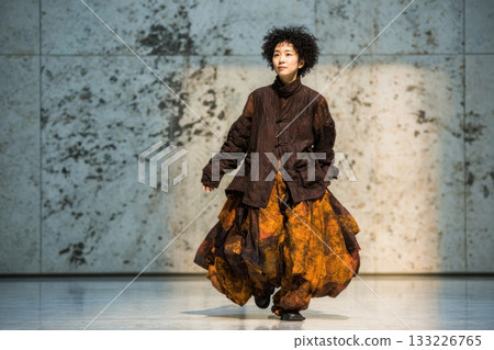 Female model showcasing unique fashion design on minimalist stage 133226765