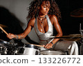 Female drummer performing passionately on stage with vibrant energy 133226772