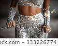 Sparkling performer holding sparklers in dazzling silver outfit with flair 133226774