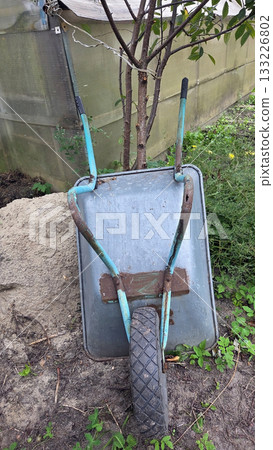 Rustic vegetable garden setting with wheelbarrow for gardening and cultivation inspiration. Vertical poster 133226802