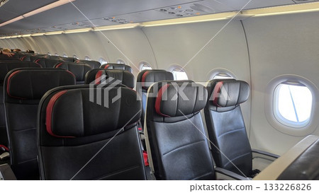 Comfortable airplane interior seating with empty aisle in a modern passenger aircraft cabin Comfortable airplane interior seating with empty aisle in a modern passenger aircraft cabin 133226826