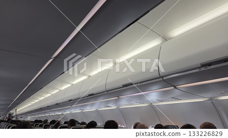 Passenger airplane cabin interior with overhead luggage compartments in flight 133226829